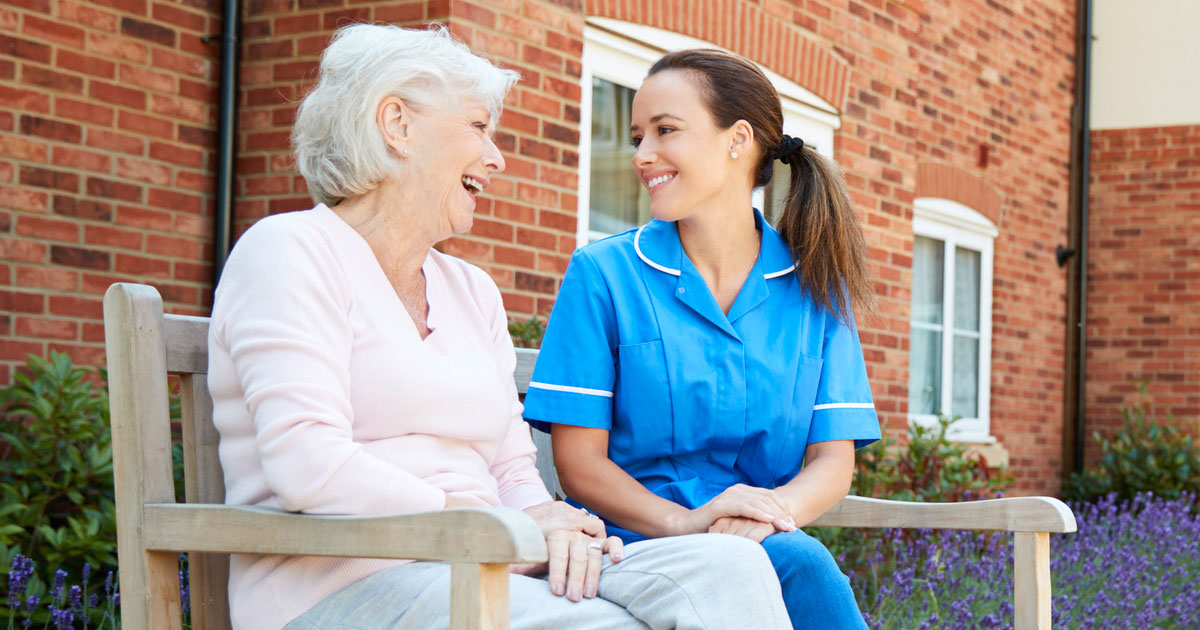 Senior Woman and Nurse Talking on Bench