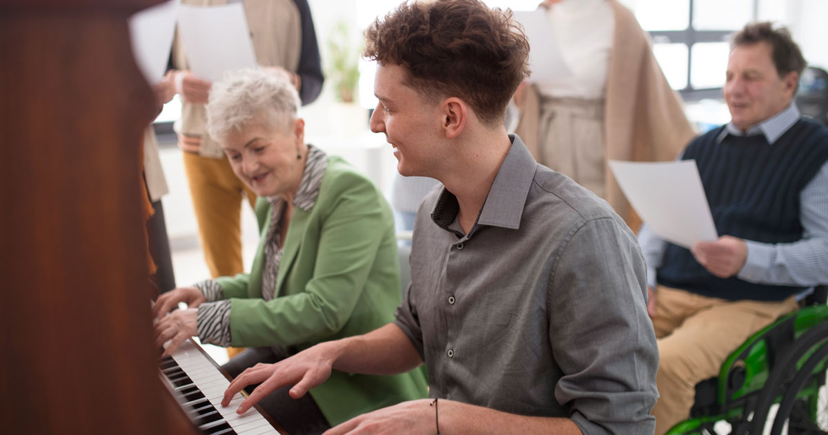 Senior Woman Playing Piano With Young Man