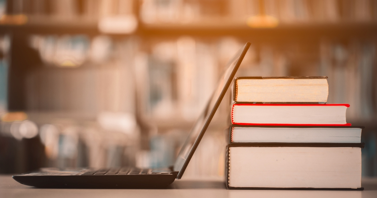 Laptop Resting Against Stack of Books