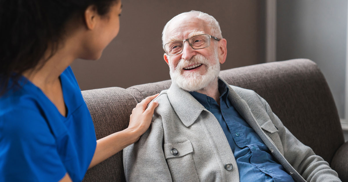 Female Caregiver Chatting With Elderly Man