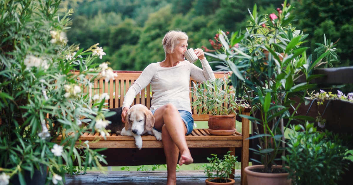 Woman Sipping Drink on Bench With Dog