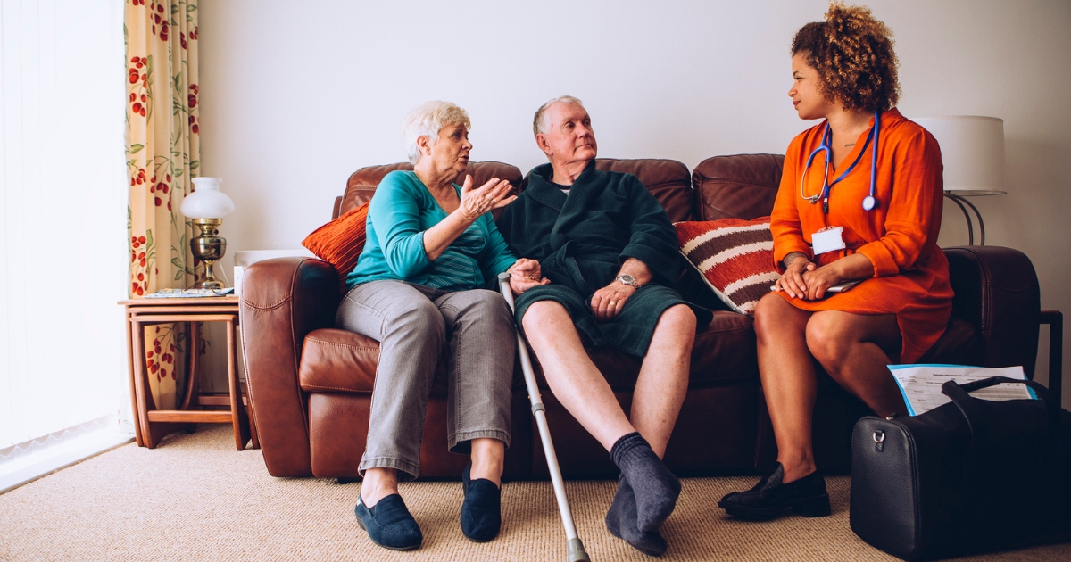 Elderly Couple Sitting With Caregiver