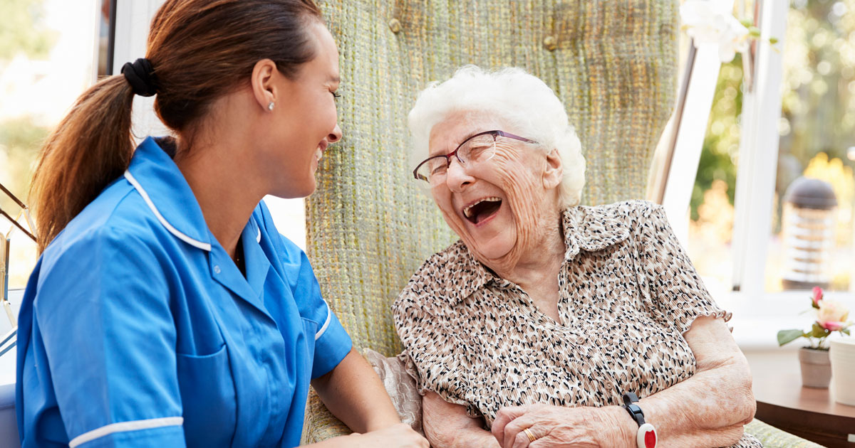 Senior Woman Sitting Laughing With Nurse