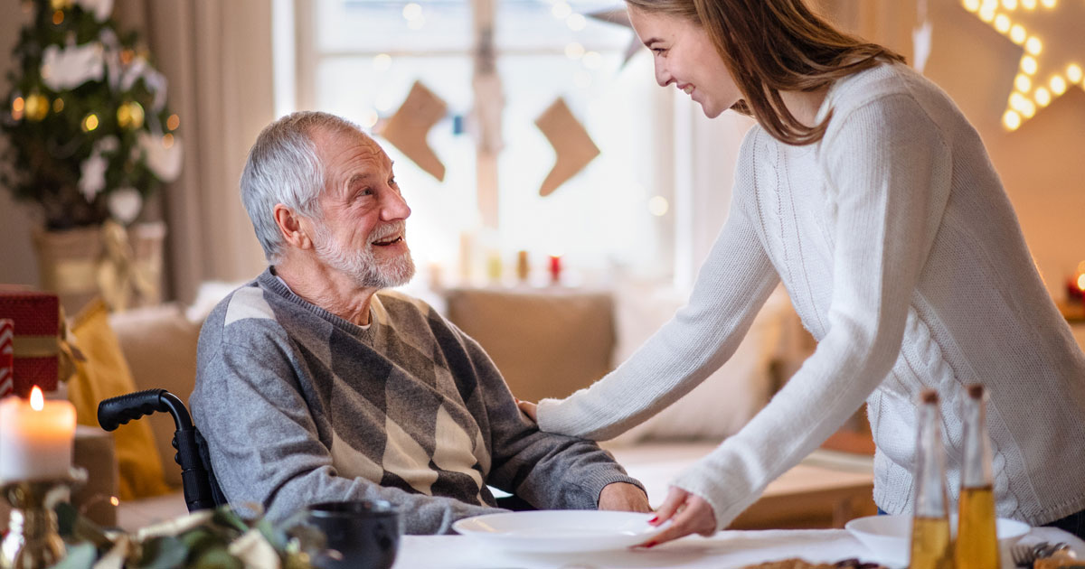 Young Woman With Homebound Grandpa During Christmas